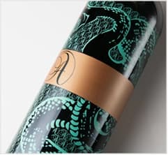 Silk-screen style label with teal pattern and gold band on a bottle